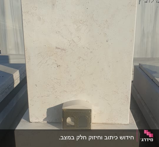 מצבת קיר משיש בהיר עם כיתוב מובלט ובית נר מותקן